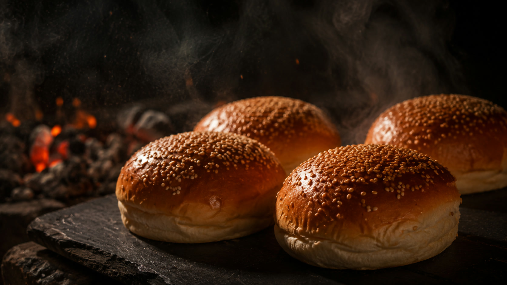 Fırından yeni çıkmış susamlı burger ekmekleri, arkada közler